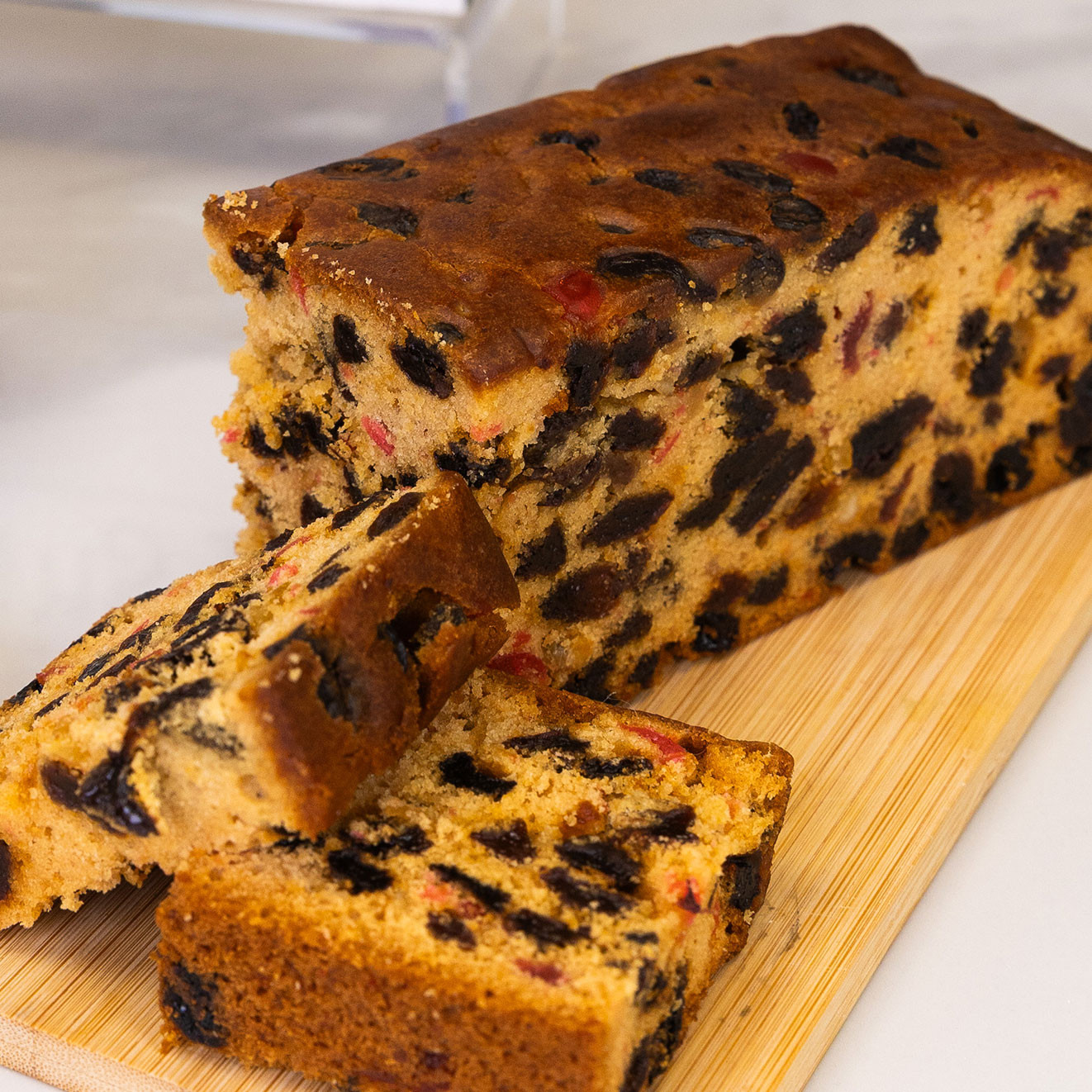 Traditional rich fruit cake sliced on a wooden serving board, packed with juicy raisins, currants and candied fruit for a classic indulgent treat.