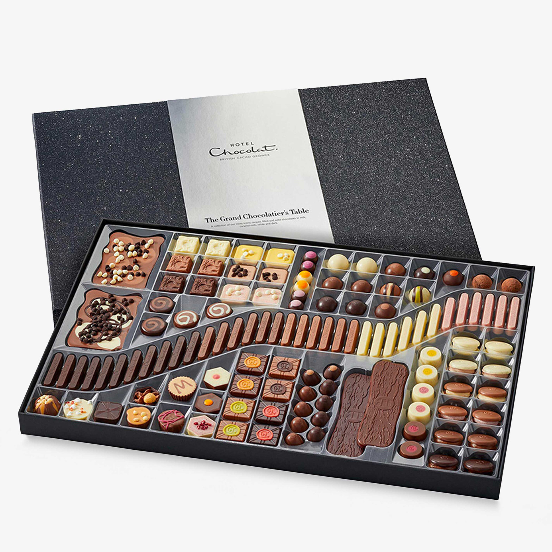 Hotel Chocolat The Grand Chocolatier’s Table, shown open with a large assortment of chocolates, truffles, chocolate fingers, slabs and other treats in a black presentation tray.