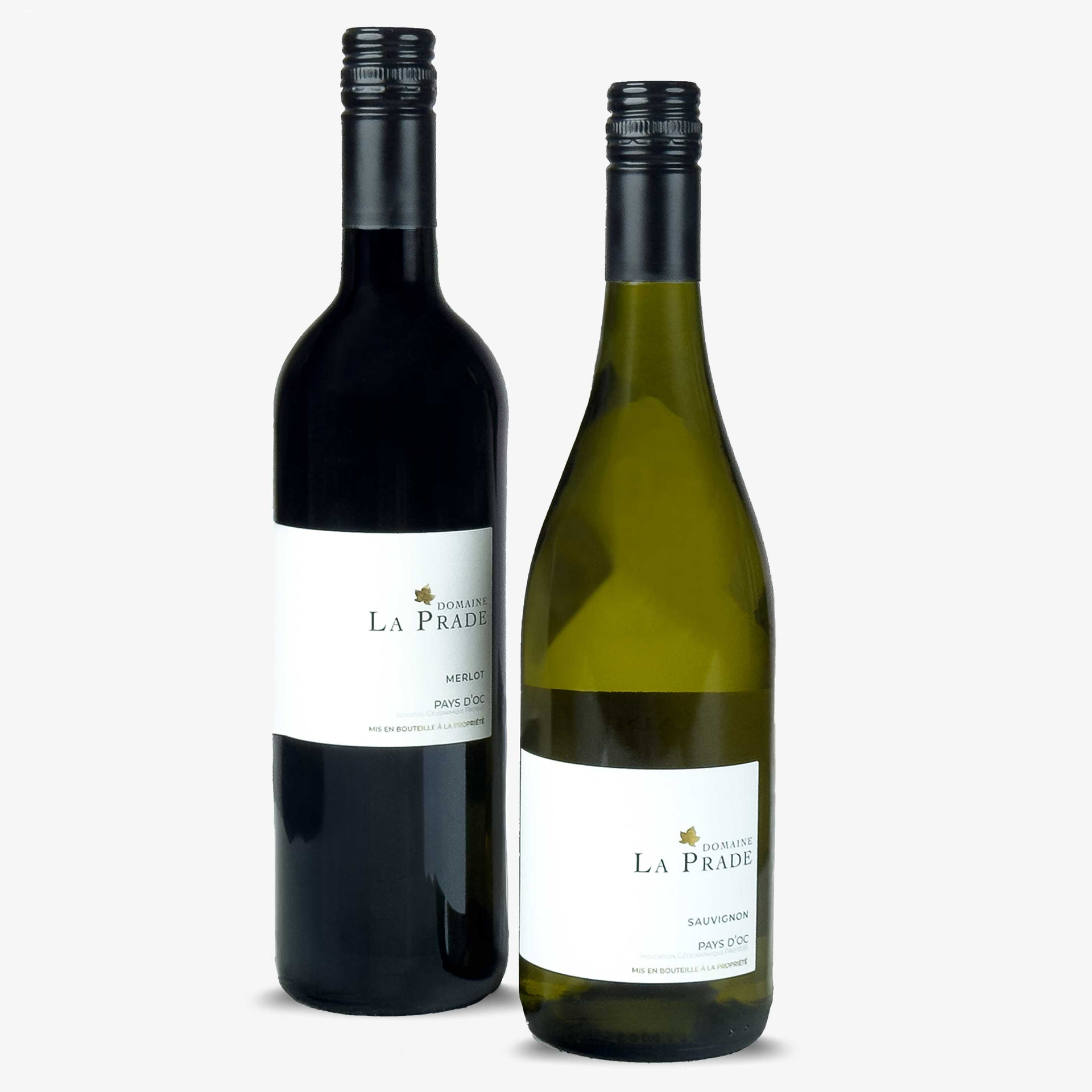 Two Domaine La Prade Pays d’Oc wines from France: a Merlot red wine in a dark bottle and a Sauvignon white wine in a green bottle, both with black screw caps and minimalist white labels.