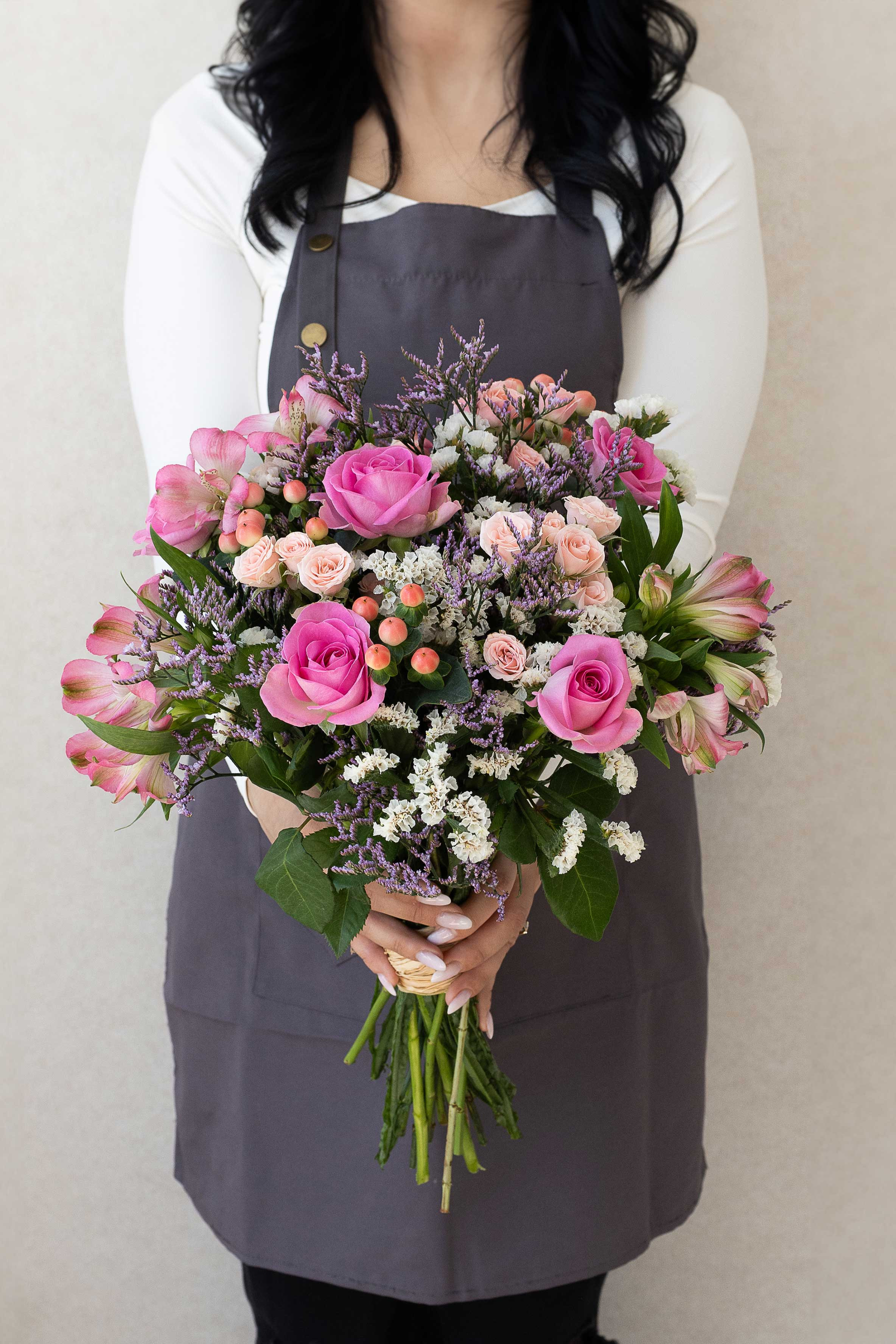 Florist holding a pink and lilac bouquet.