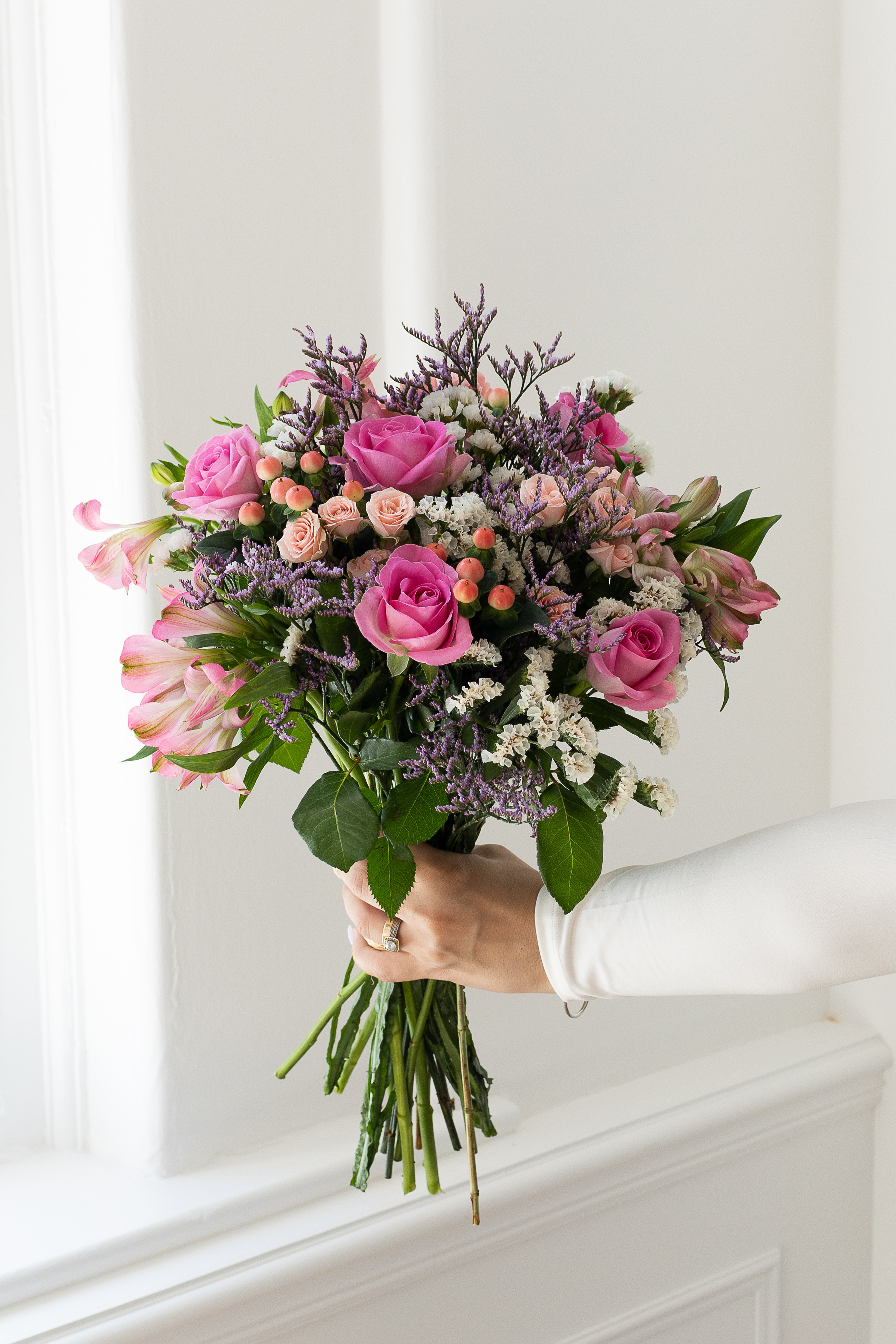Pink rose bouquet with statice, alstroemeria, and berries.
