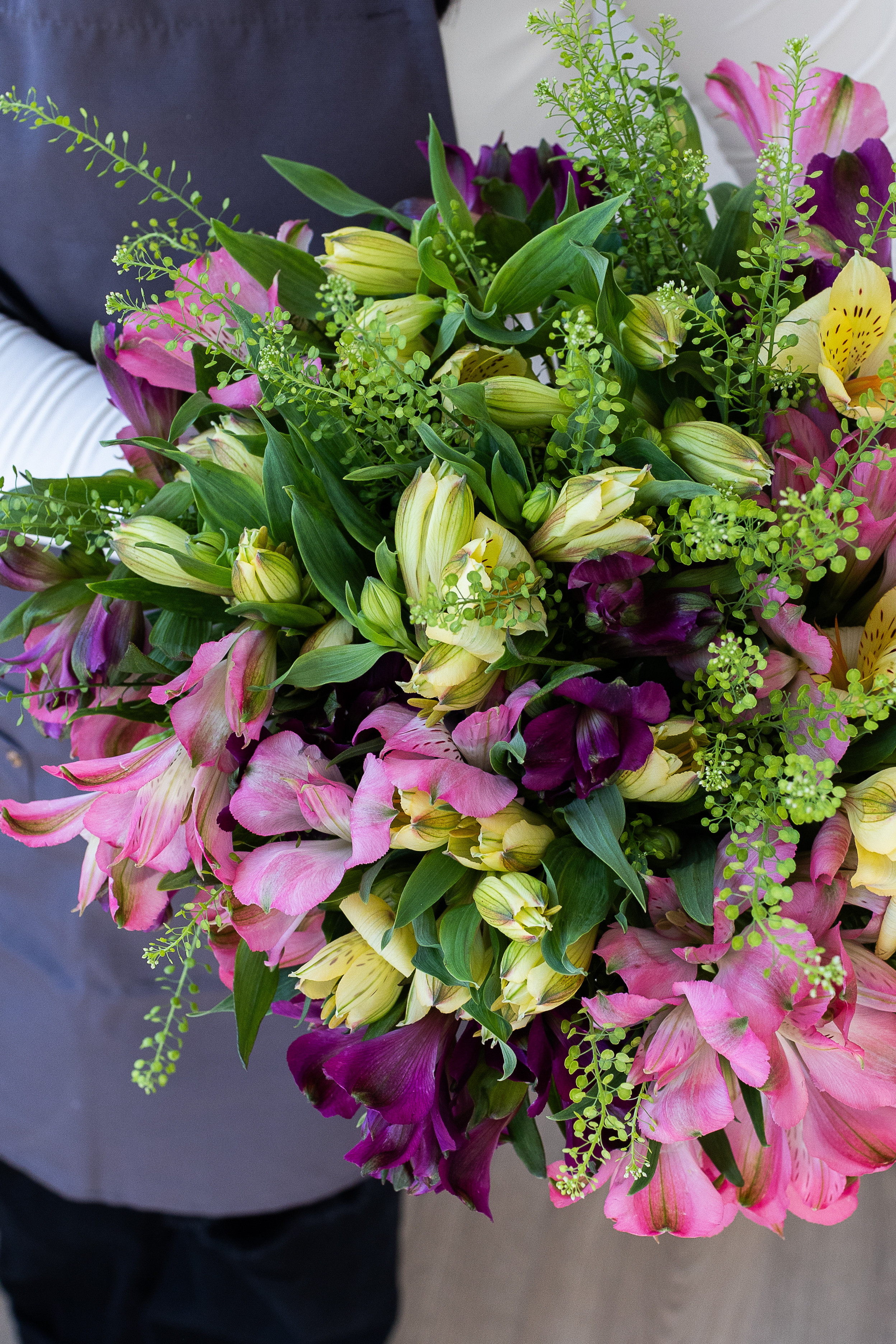 Close-up of pink, burgundy, and yellow alstroemeria flowers with greenery.
