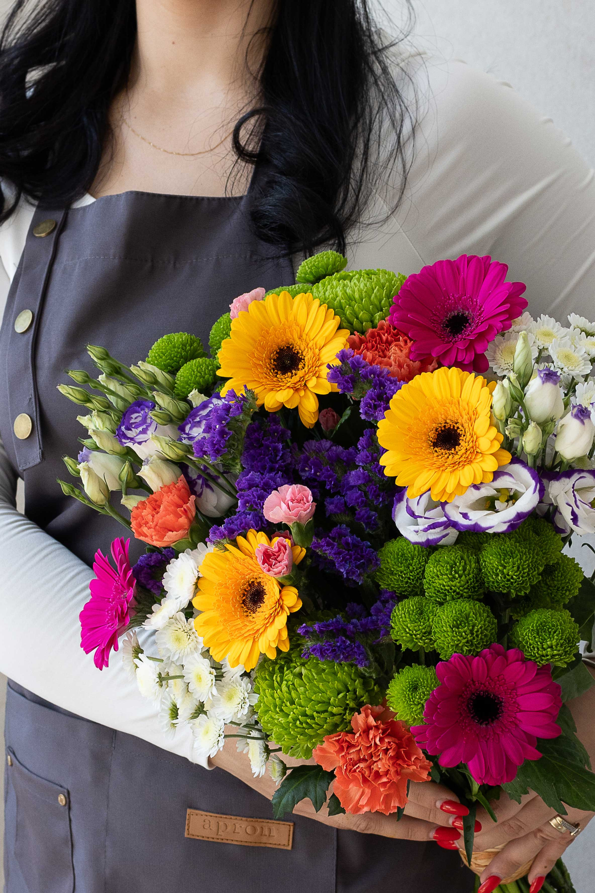 Bright mixed bouquet with gerberas, chrysanthemums, carnations, and purple statice.