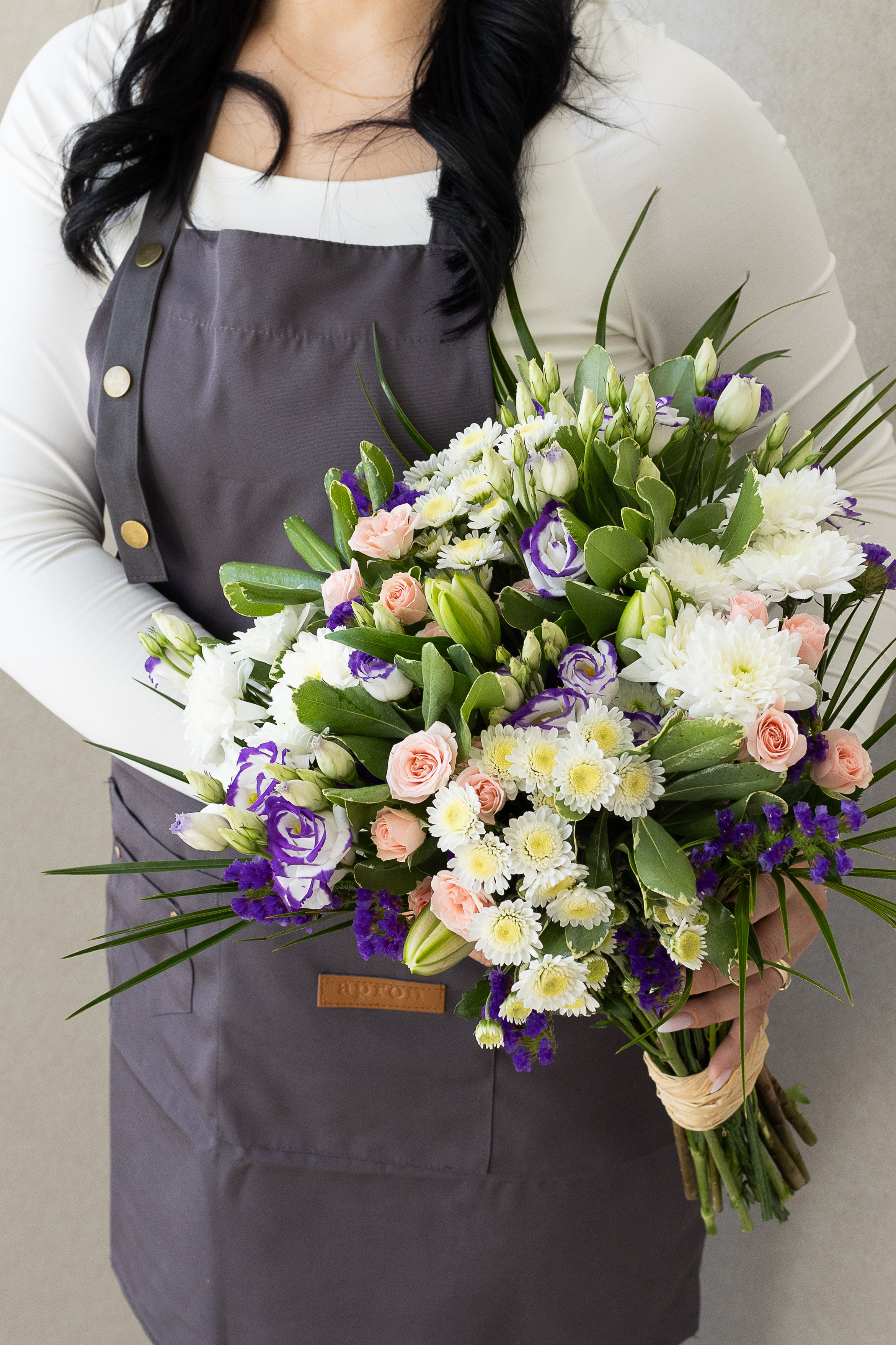 Mixed pastel bouquet with pink roses, purple lisianthus, and white blooms.