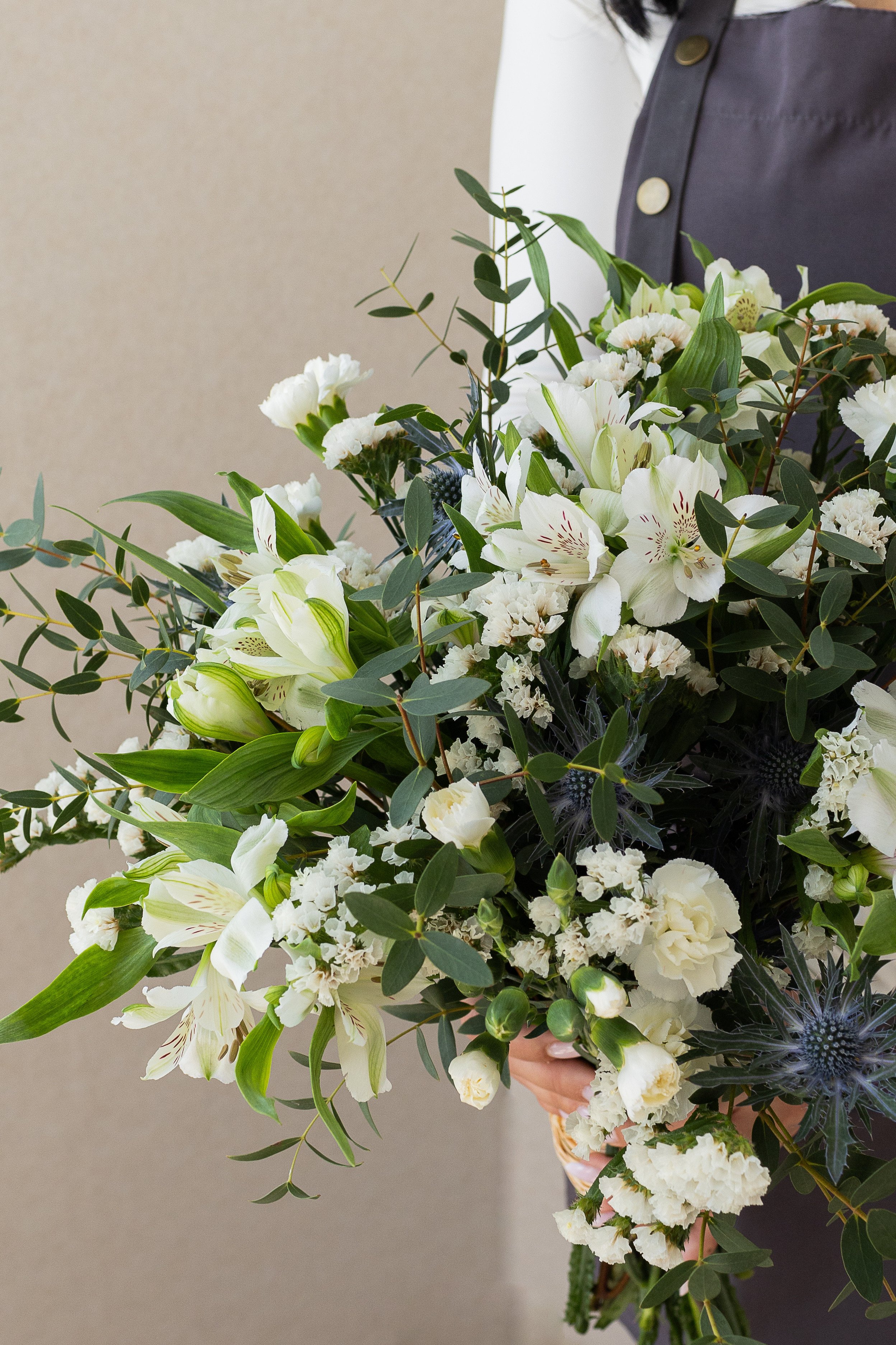 Close-up of white flowers, eucalyptus, and blue thistles.