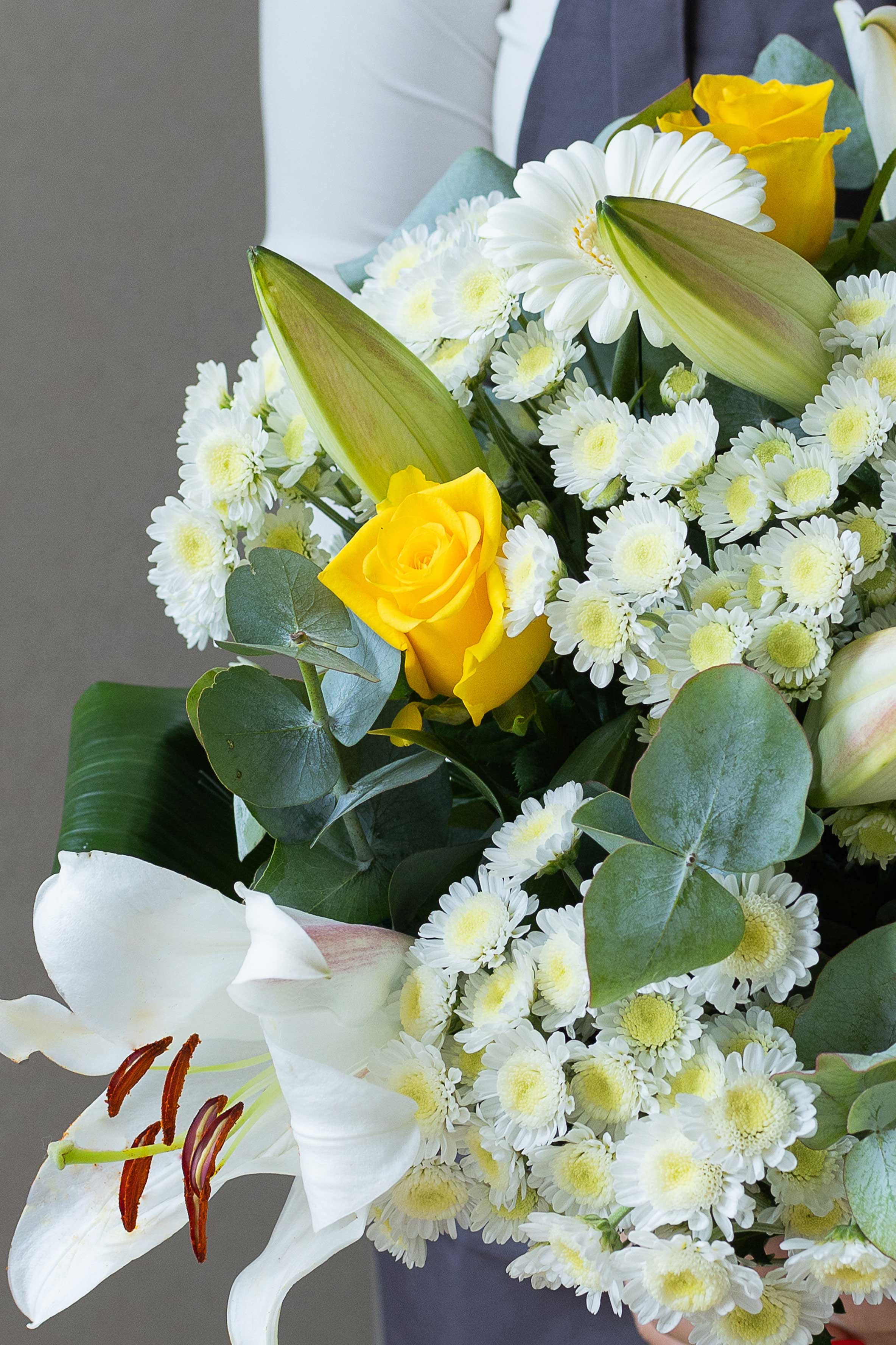 Close-up of yellow roses, white chrysanthemums, and lilies.