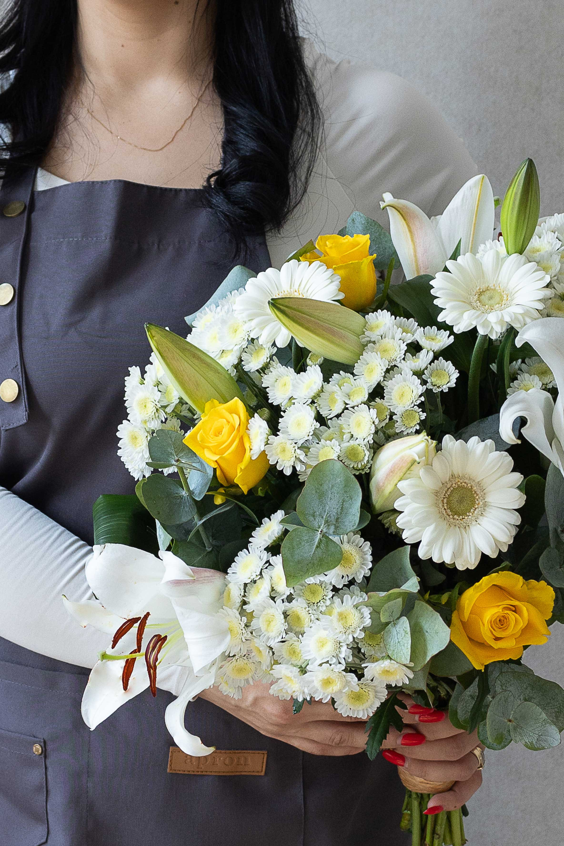 Mixed bouquet with white lilies, yellow roses, and eucalyptus.