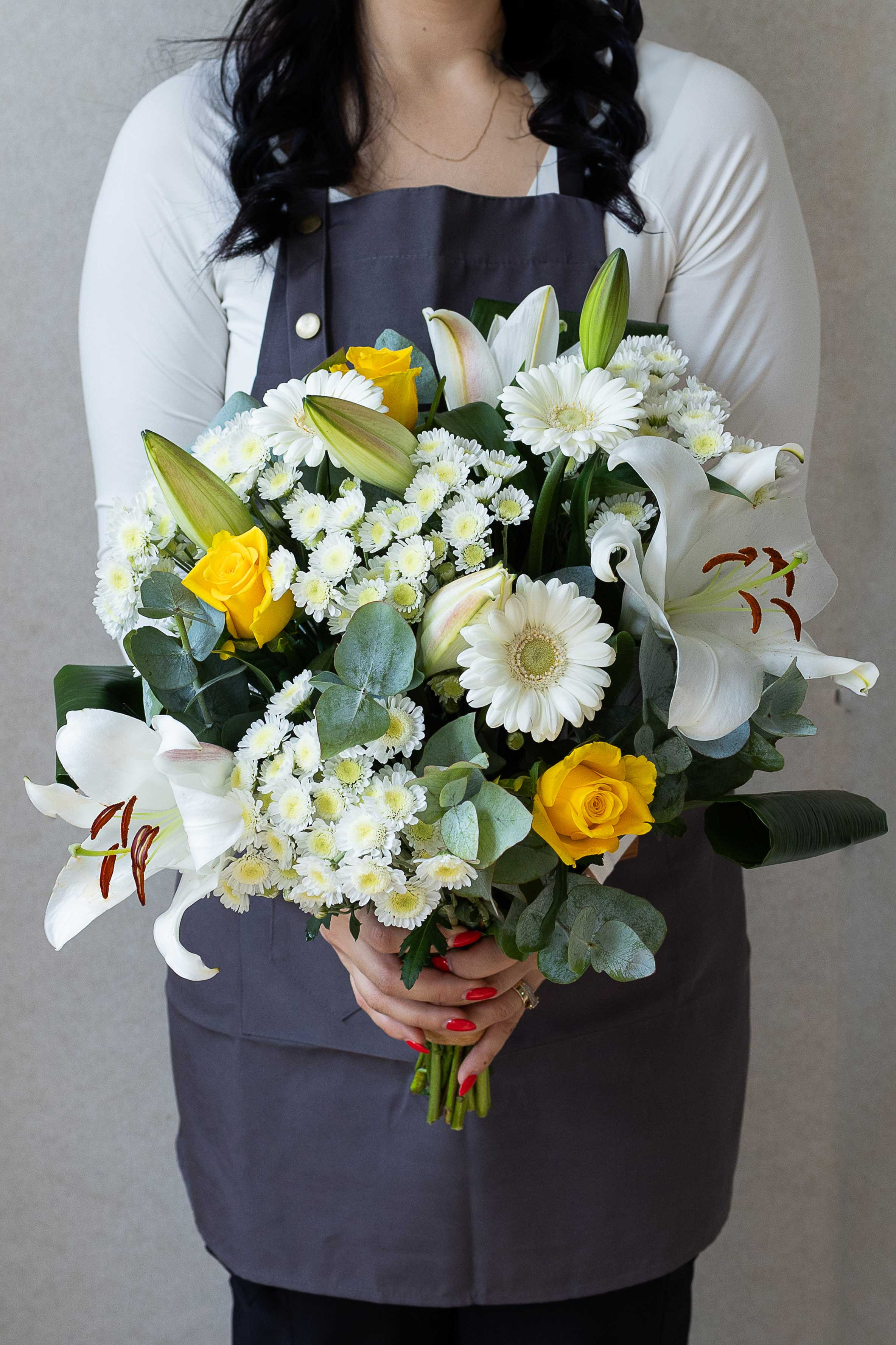 Florist holding a white and yellow mixed flower bouquet.