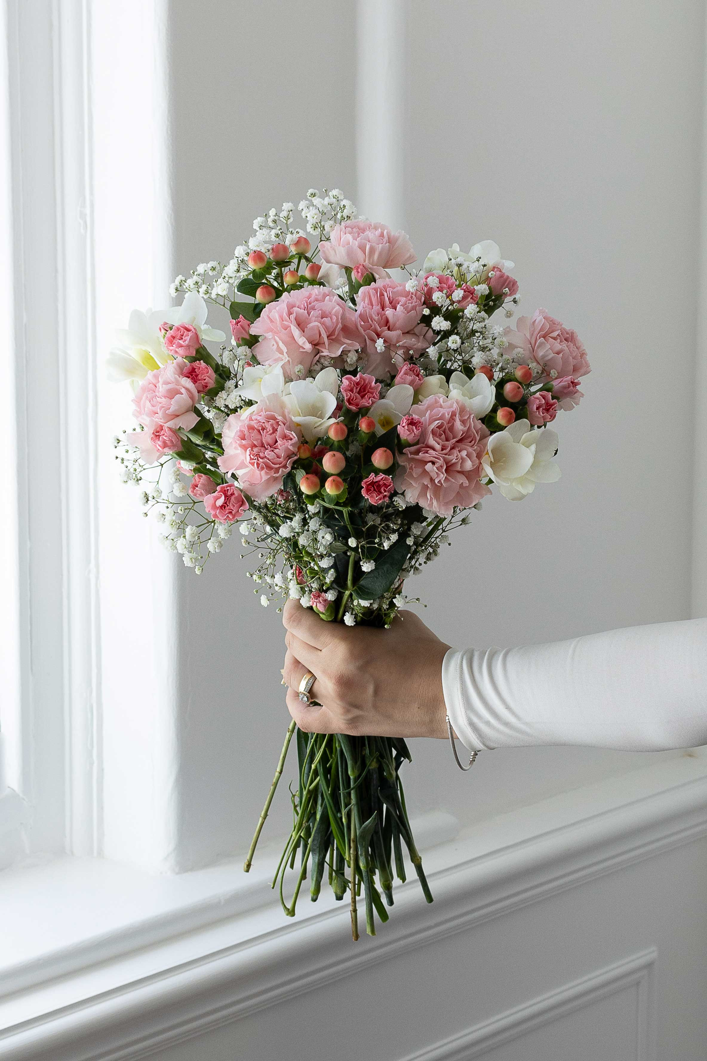 Pastel pink and white bouquet with carnations, freesia, and gypsophila.