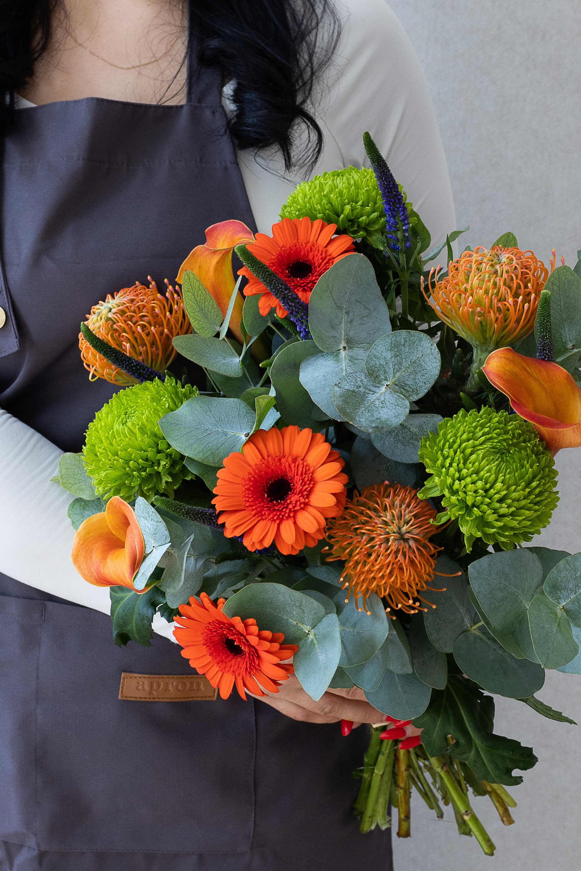 Orange gerbera, pincushion protea, calla lily, and eucalyptus bouquet.