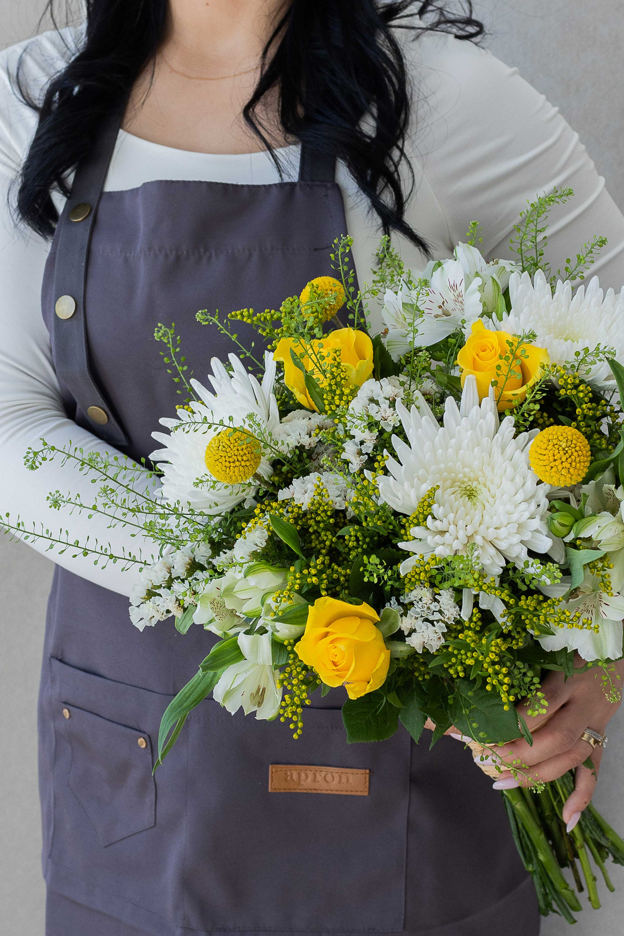 Florist holding a bright yellow and white mixed bouquet.