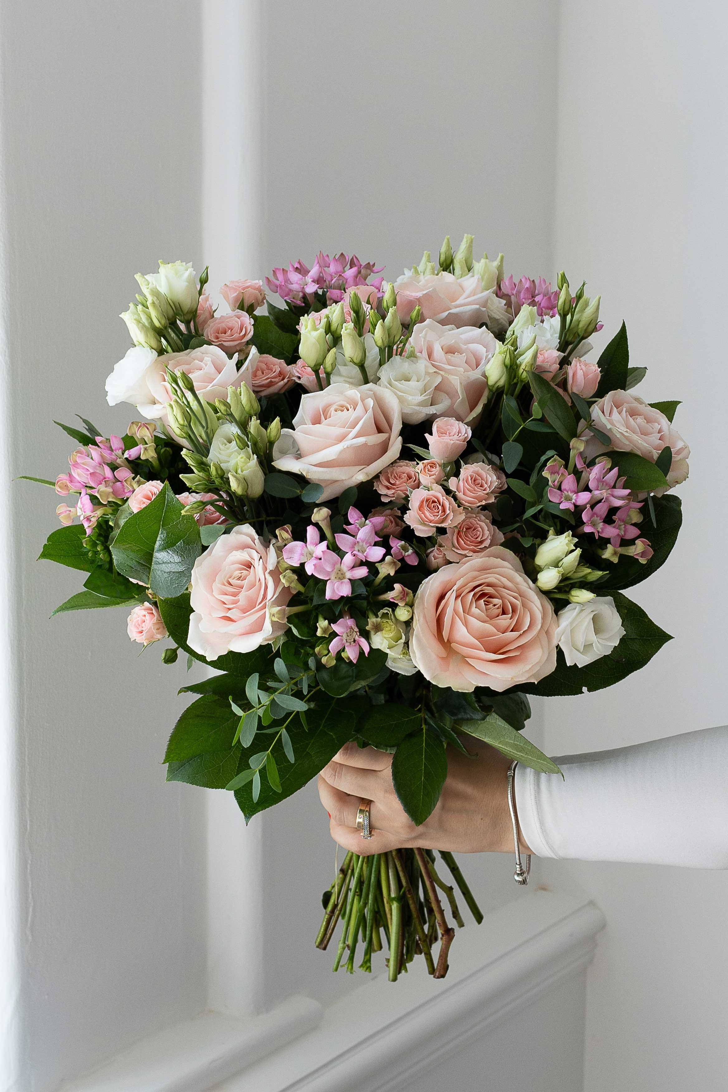 Pastel pink and white bouquet with roses and greenery.