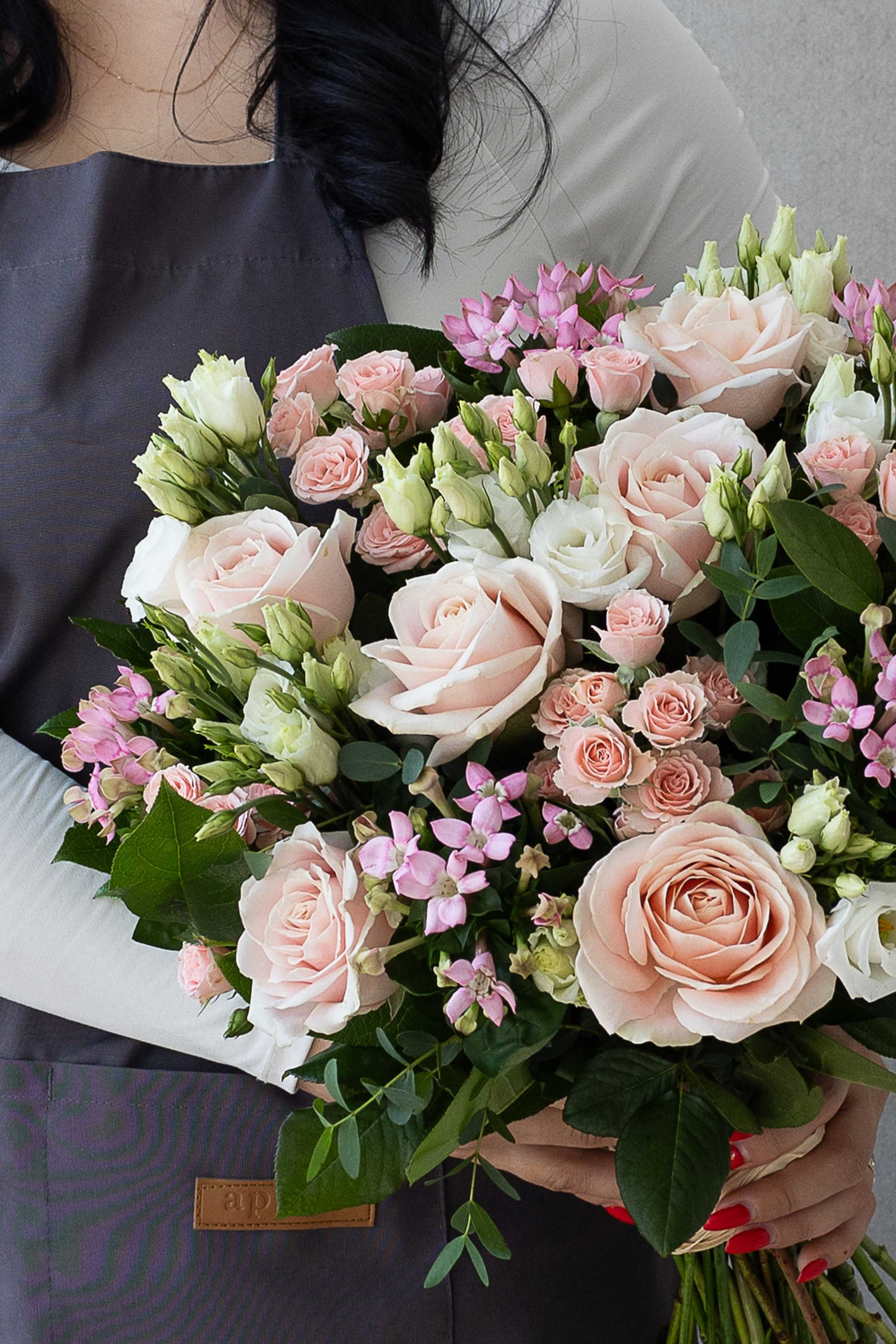 Close-up of blush roses, pink spray roses, and white lisianthus.