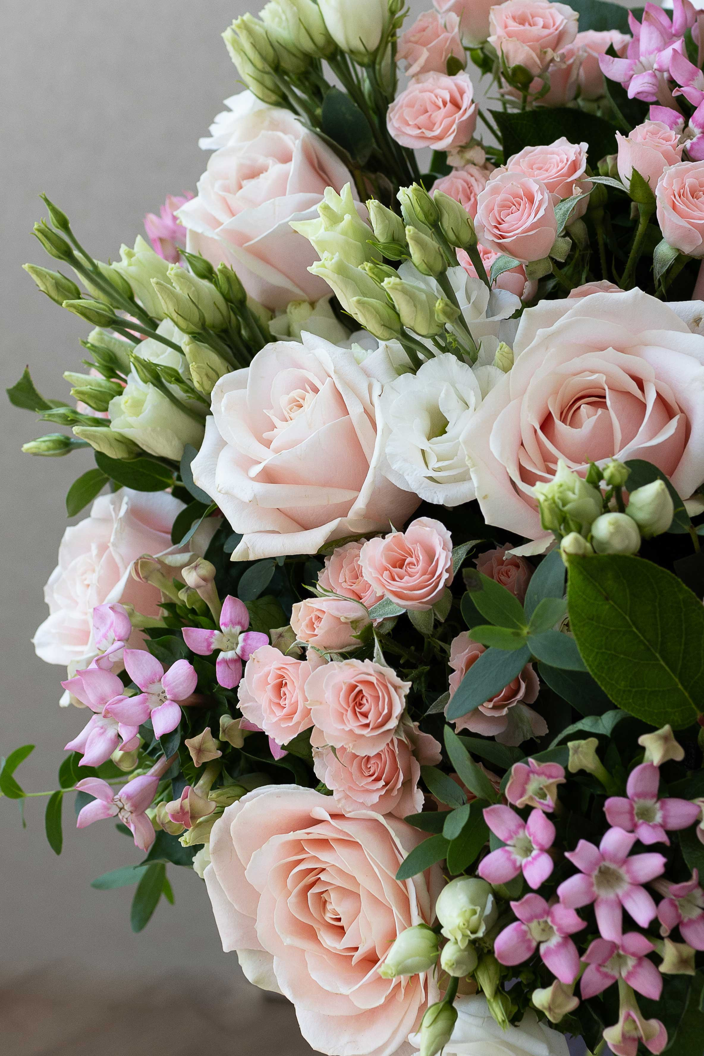 Close-up of blush roses, spray roses, and white lisianthus.
