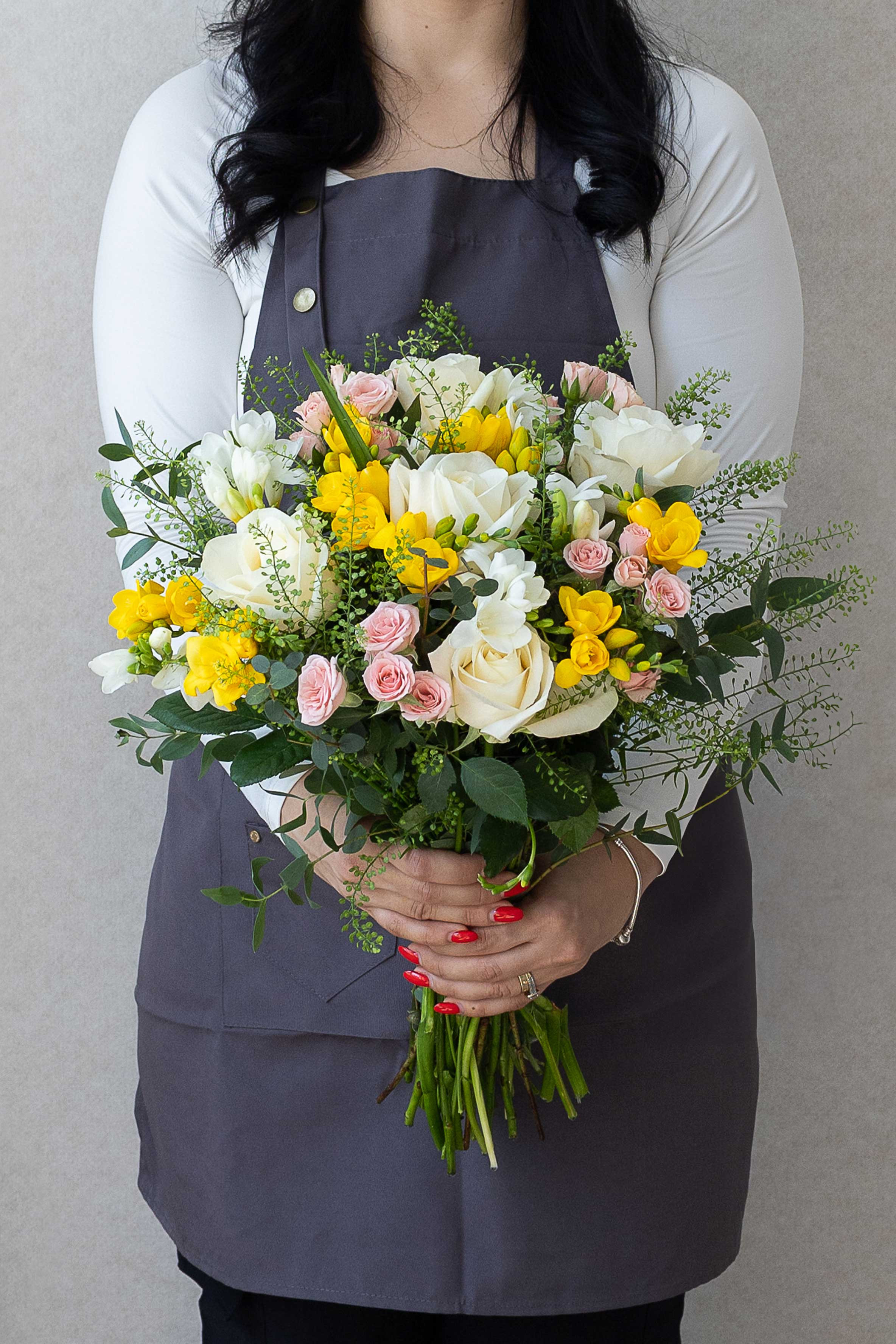 White roses, pink spray roses, and yellow freesia bouquet.