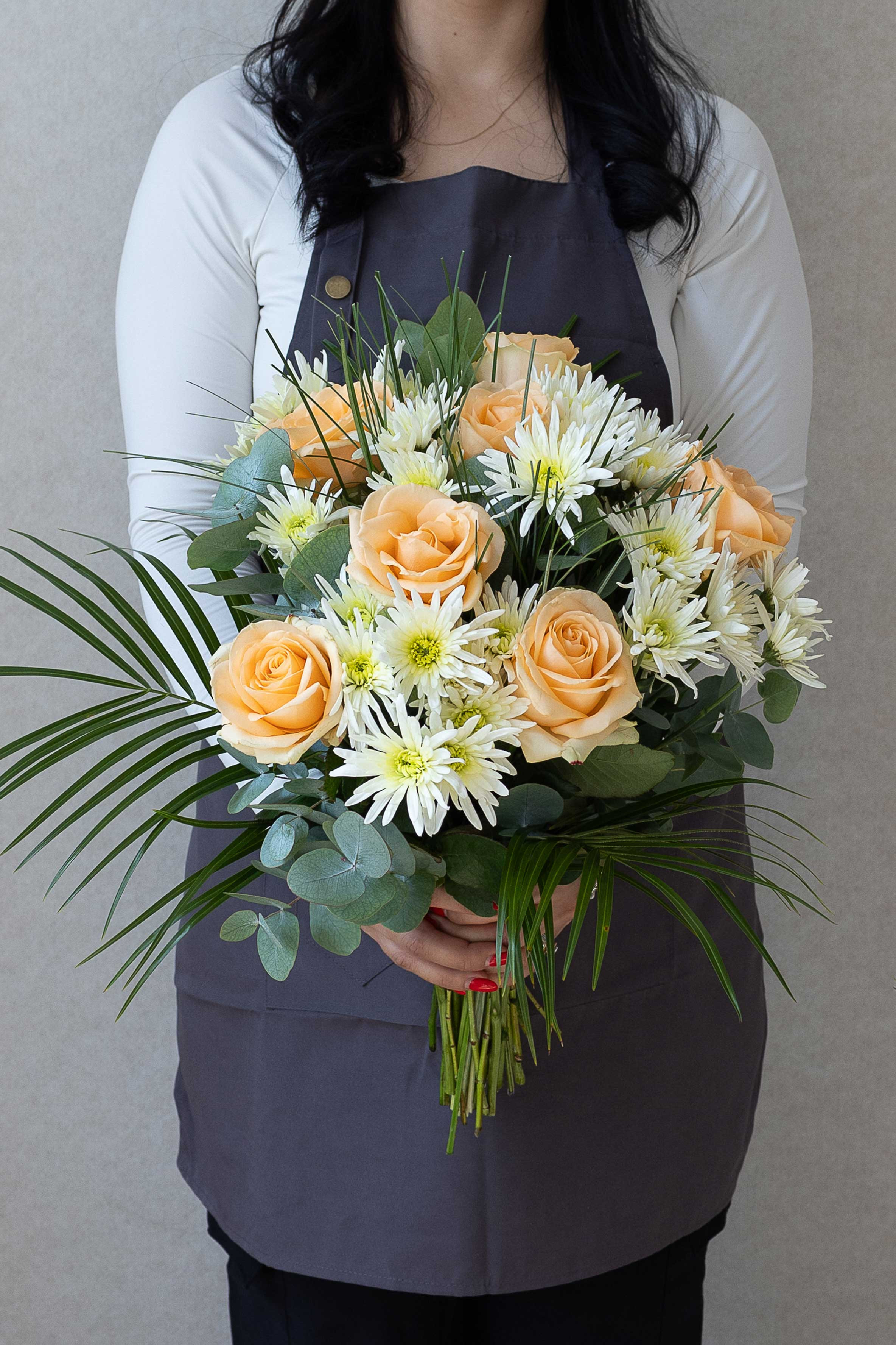 Hand-tied bouquet of peach roses, white chrysanthemums, and greenery.