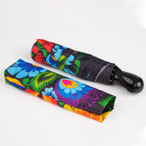 A close-up view of the Folkstar Lowicz Floral Pattern Compact Umbrella, featuring a sleek black canopy adorned with a vibrant floral folk print. The umbrella is compact and foldable, with a matching cover, automatic opening and closing, and a secure velcro strap. Its stylish design captures the essence of Polish heritage