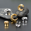 SoScene Doom and Gloom Moon Saddle Spreaders Ear Plugs, decorative crescent moon-shaped metallic ear plugs with star cutouts in gold and silver finishes displayed on stones.