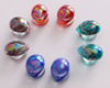 SoScene Teal Iridescent Alien Green Glass Double Flare Ear Plugs, colorful iridescent alien head-shaped glass ear plugs arranged in a circle on a white background.