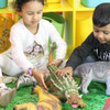 children playing with 2 jumbo large dinosaur toys - a 21-inch spinosaurus and a 21-inch ankylosaurus
