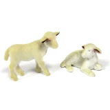 Two white toy lamb figures from a farm animal toys set, one standing and one lying down