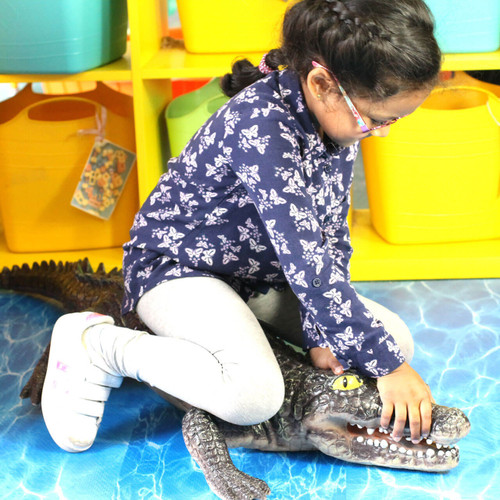 child sat on a large crocodile toy