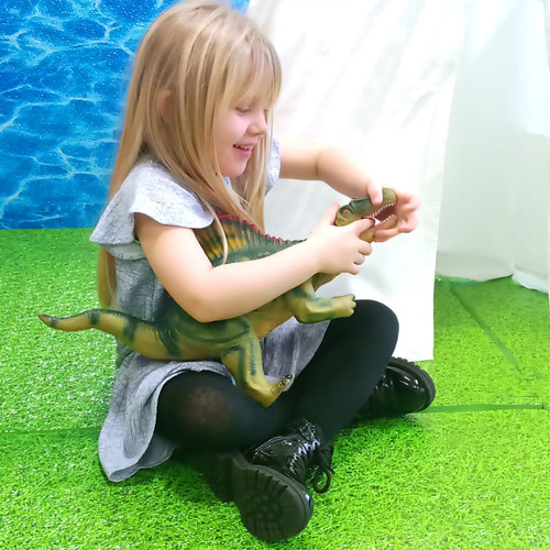 Girl playing with 2 jumbo large dinosaur toys - a 21-inch spinosaurus and a 21-inch ankylosaurus