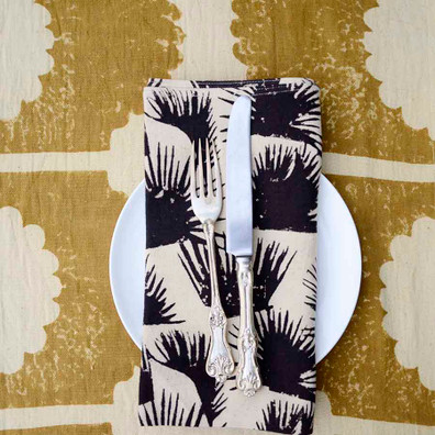 Block Print Fern Black Napkin on a white dish with a knife on top.