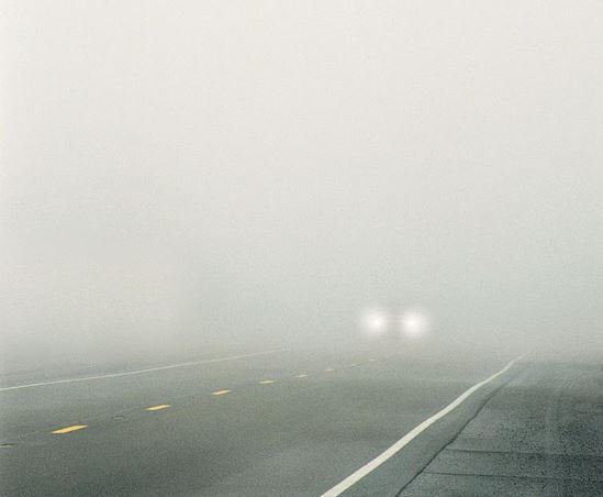 A Vehicle's Headlight are Barely Visible in Dense Winter Fog