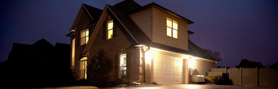 Champion Home Standby Generator on a driveway by a two-story home with lights.