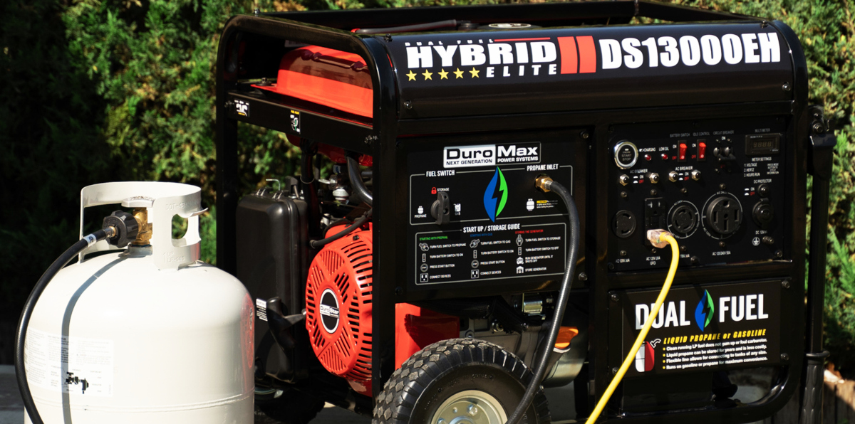 DuroStar DS13000EH 10500 Watts / Max 13000 Watt Generator Dual Fuel Electric Start Shown with LP Tank next to arbor vitae hedge