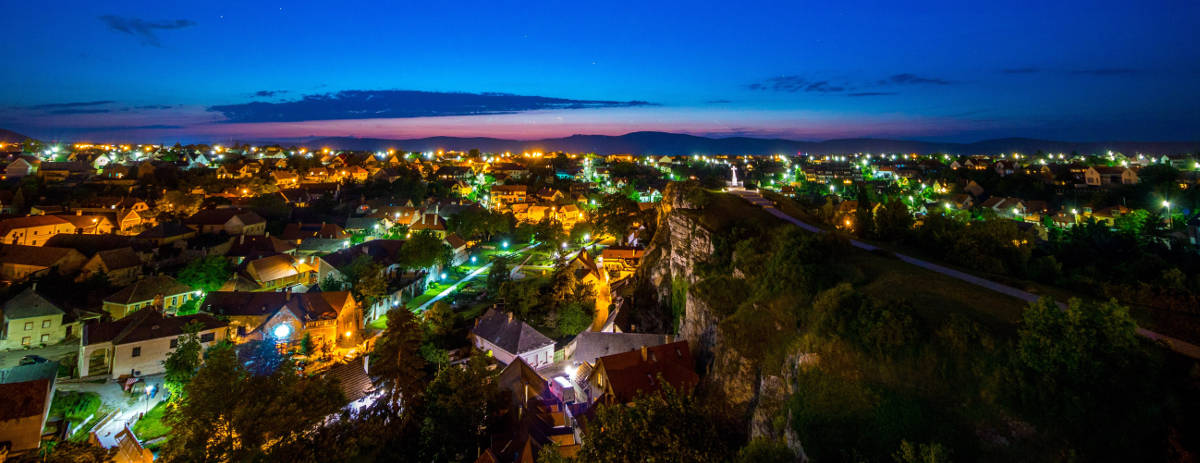 A city glows in the twilight with power outages in dark neighborhoods.