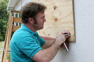 Man Boarding up a House with Plywood