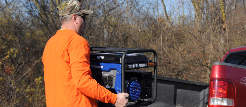 Man Lifting a Westinghouse WGen3600 Portable Generator Onto a Pickup Truck Bed