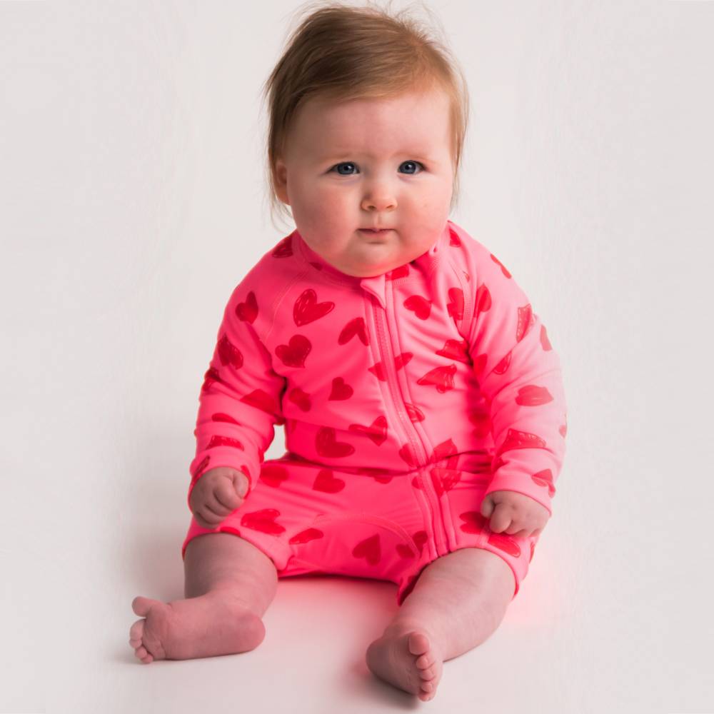 Baby sitting in Pink Hearts Shortie Swimmers 