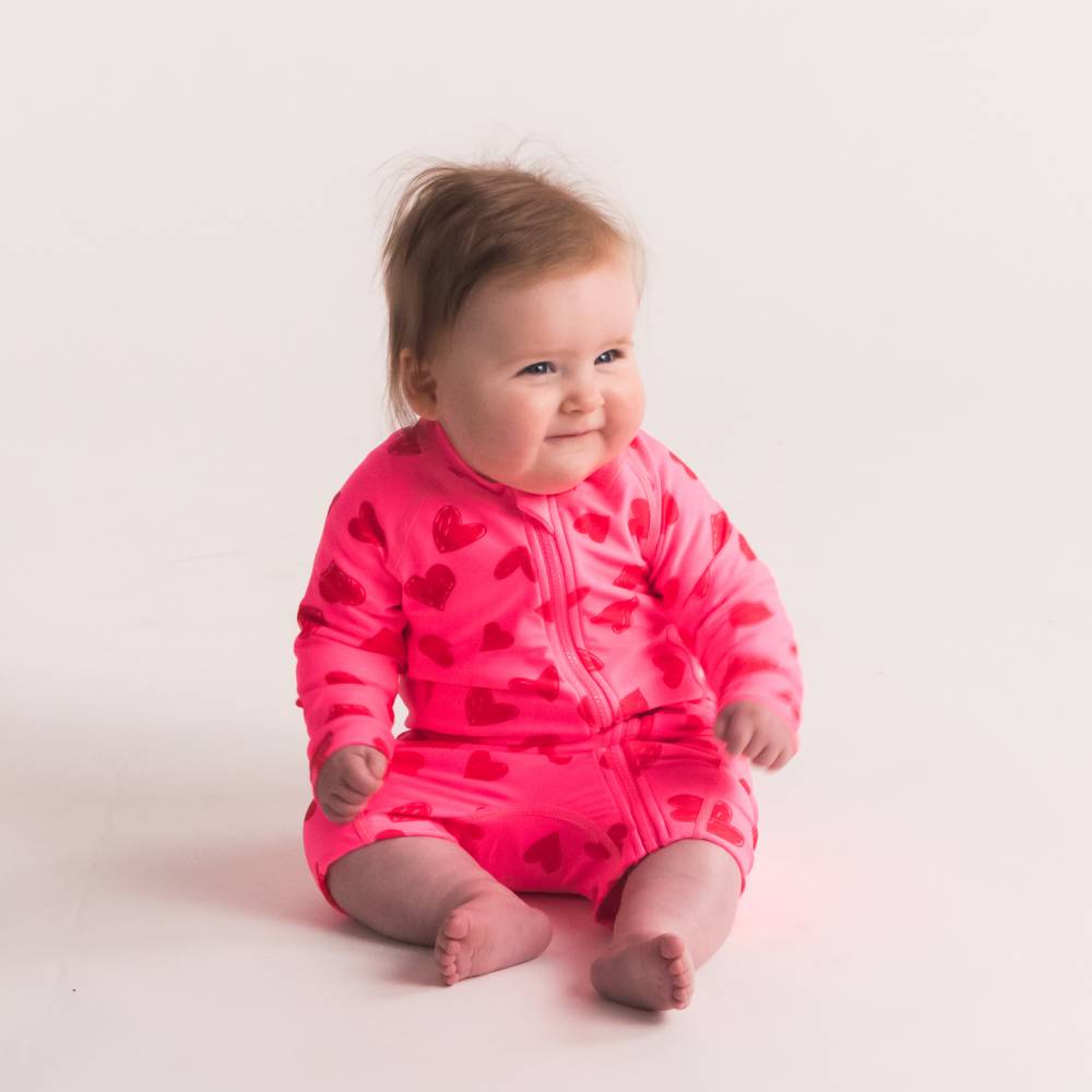Baby sitting in Pink Hearts Shortie Swimmers 