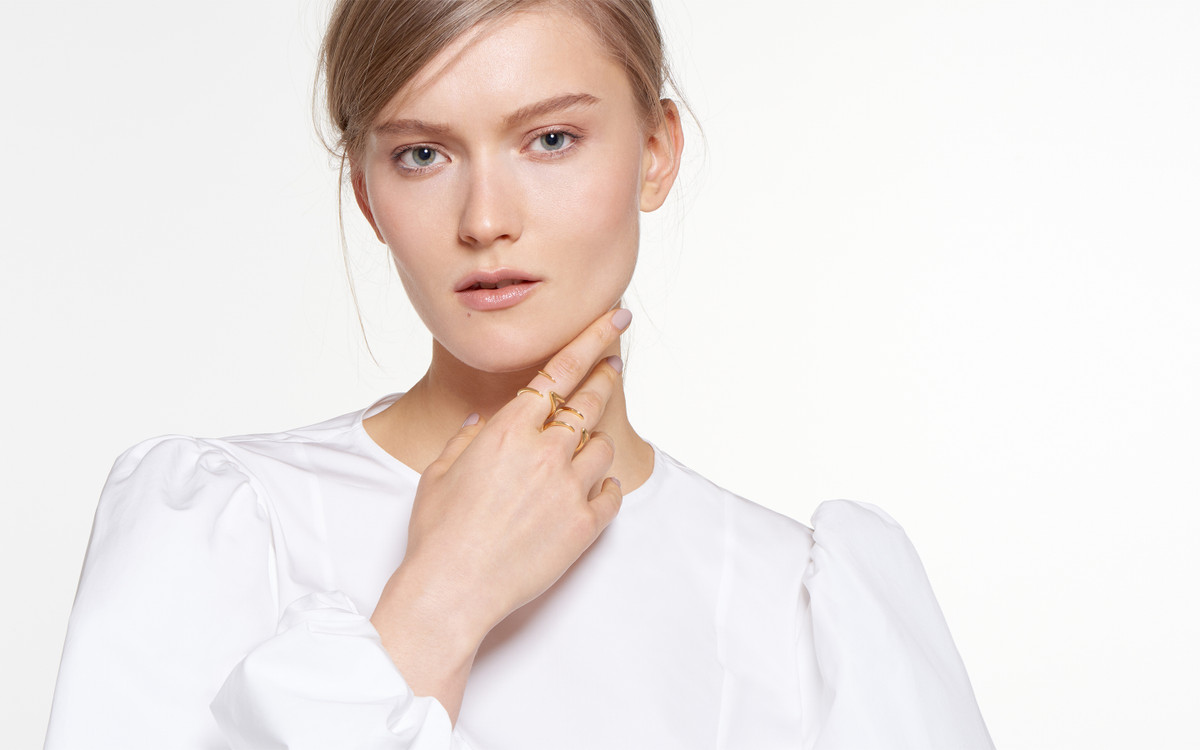 model gazing pensively sporting 18 karat gold ring in horn design