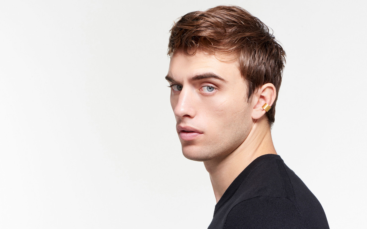22 karat gold ear cuff in crescent shape on attractive male model staring stoically