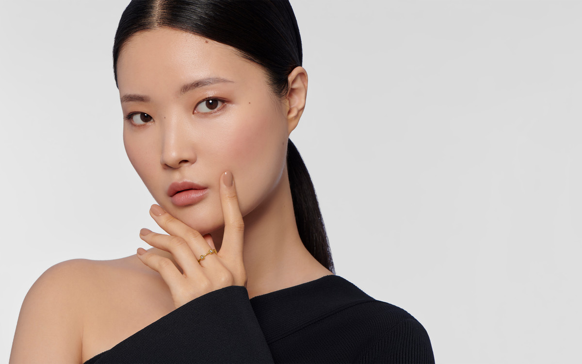 Female model wearing a 22 karat gold ring with gemstones.