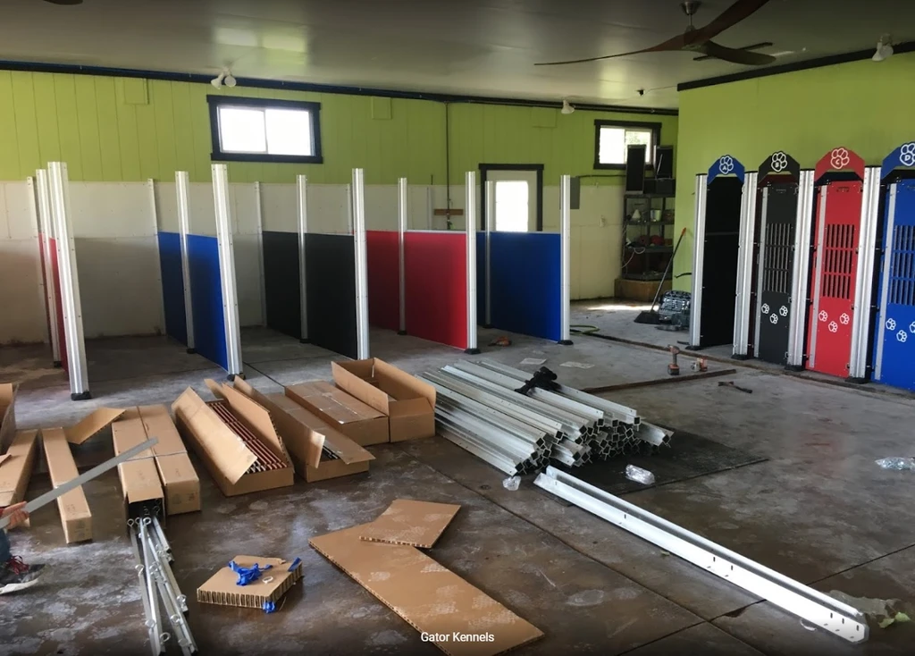 Anti-fight kennel run panels being installed. Dog kennel panels are a mix of red, black, blue, and tan to match the front of the dog kennels.