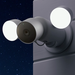 Nest cam with floodlights attached to the the exterior of the house with lights on during the night.