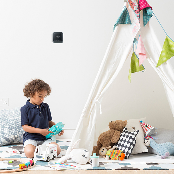 Child playing in playroom with thermostat on the wall