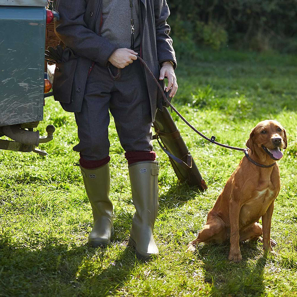 Man in wellington boots standing next to a dog