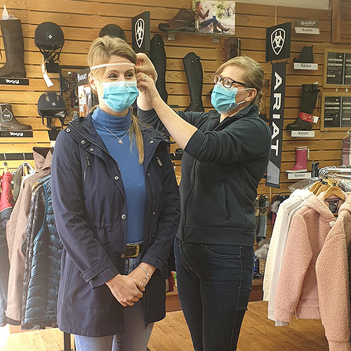 woman measuring another woman in shop for hat fitting