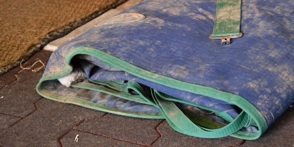 Dirty horse rug laying on a stable floor