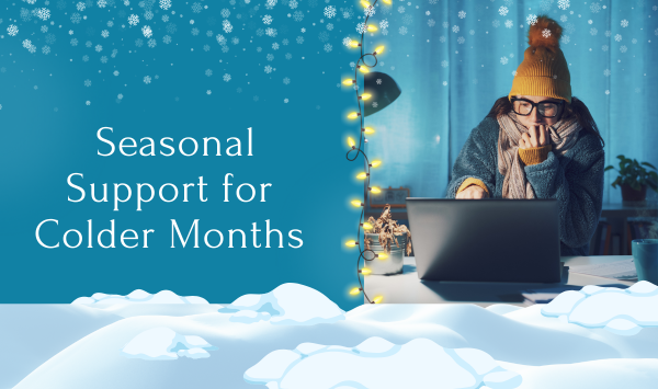 Person working on a laptop indoors during winter, bundled in a hat and scarf, representing daily wellness support during colder months.