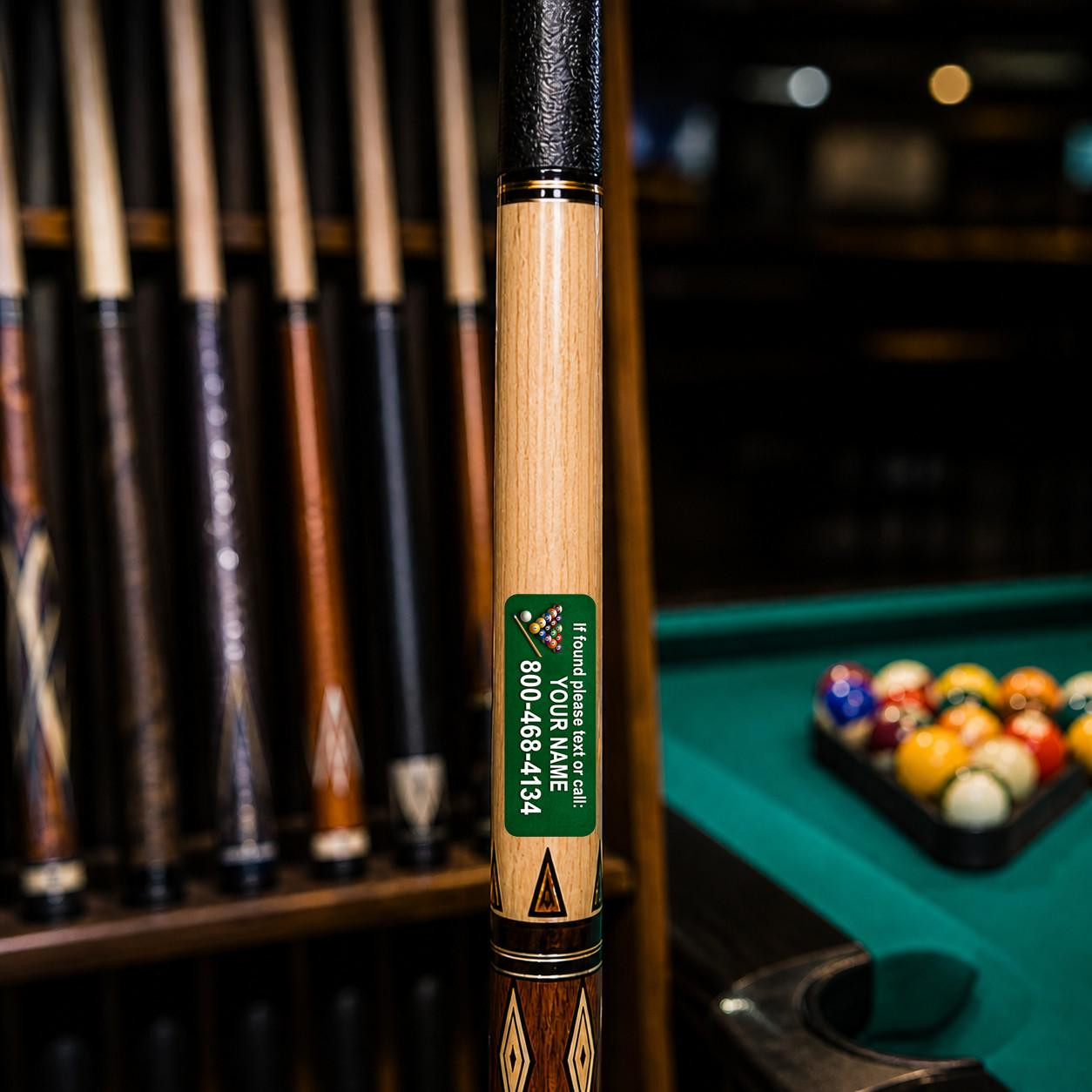 Stinky Lockers Personalized Pool Cue ID Decals, close-up of a billiard cue with custom sticker on the shaft in a pool hall with pool balls and cues in the background.