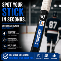 Stinky Lockers Personalized Hockey | Ringette | Lacrosse Stick Sticker, close-up image showing the waterproof, durable vinyl sticker applied to a hockey stick handle with a blue and white design, featuring the name 'Magnold' and sports logo.