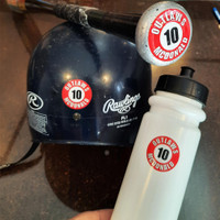 Close-up of a personalized baseball bat knob decal featuring a player name and number, designed to help youth baseball players easily identify their bat in the dugout.