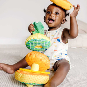 Baby playing with Melissa & Doug soft pineapple stacking toy featuring colourful yellow and green fabric rings